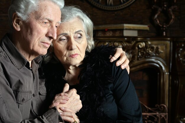 Photo portrait of sad senior couple at home hugging