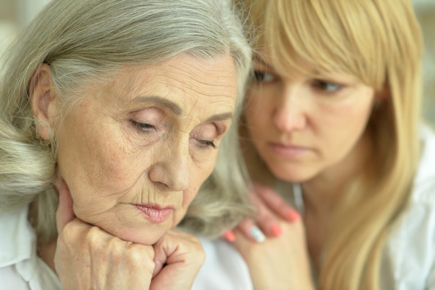 Portrait of sad senior mother with adult daughter