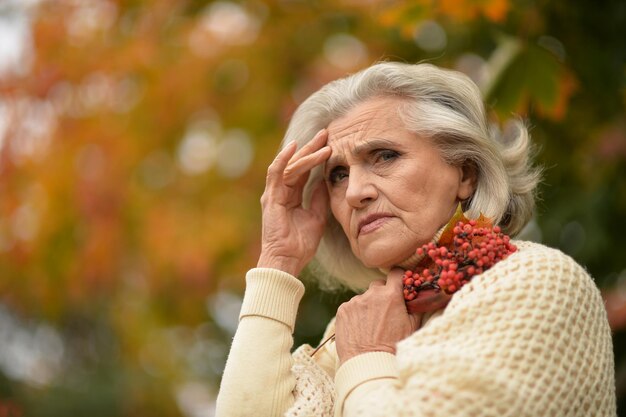 Portrait of sad senior woman in autumn park