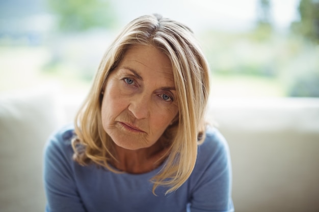 Portrait of sad senior woman sitting on bed