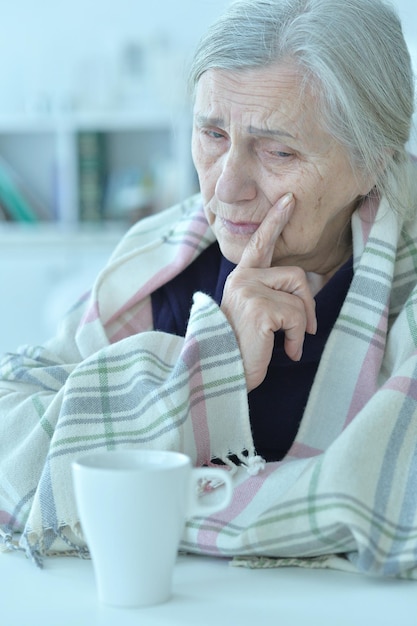 自宅で頭痛を持つ悲しい年配の女性の肖像画