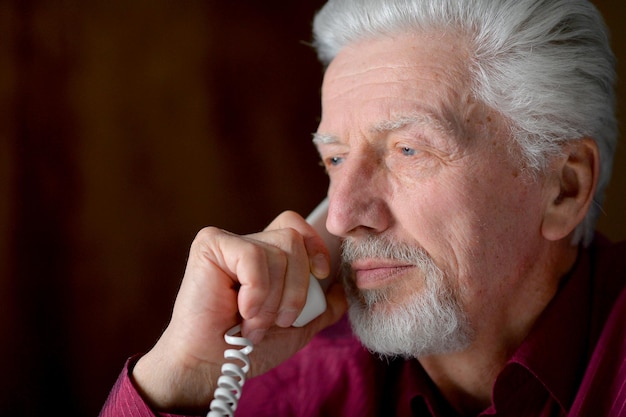 Portrait of sad sick senior man calling doctor