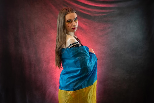 Portrait of sad Ukrainian woman wear national clothes with blue and yellow flag