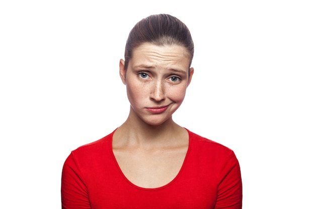 Portrait of sad unhappy woman in red tshirt with freckles studio shot