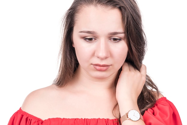 Photo portrait of sad woman in red blouse with hand near neck looking down, isolated on white background