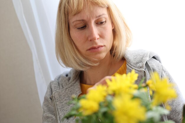 Portrait of a sad woman with flowers on a white background