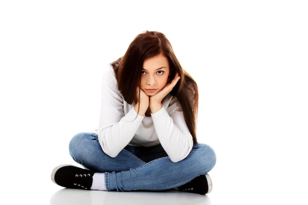 portrait of sad woman with hands on chin sitting against white background