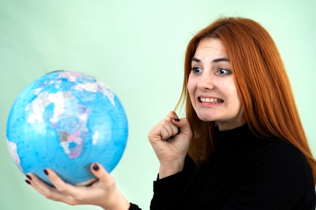 Портрет грустно беспокоит молодая женщина держит в руках географический глобус мира. Путешествия и концепция защиты планеты.