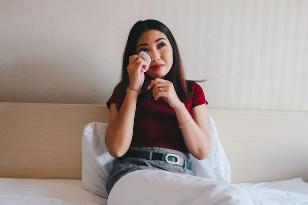 Portrait of a sad young asian woman crying on her bed