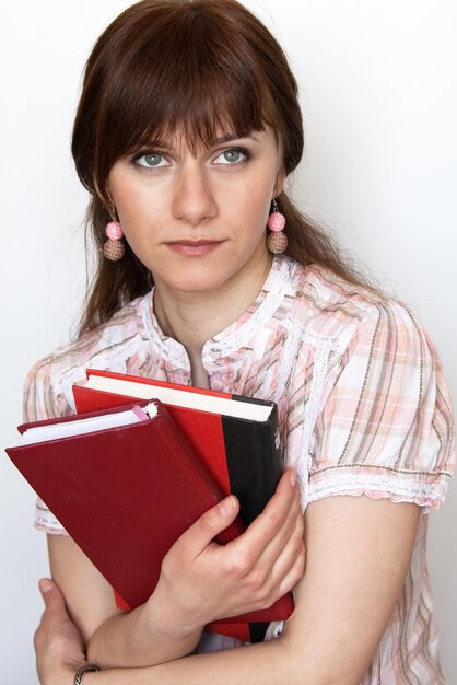 Portrait of a sad young beautiful brunette holding two books in her hands