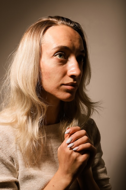 Portrait of a sad young blonde girl without makeup with loose hair