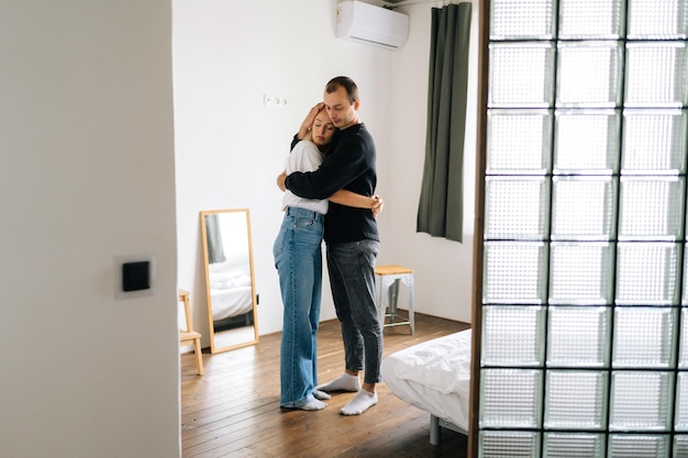 Portrait of sad young couple having relationship trouble embracing emotional issues sharing bad news at home Loving man and woman consoling each other