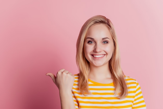 Portrait of salesman lady direct thumb side empty space on pink background