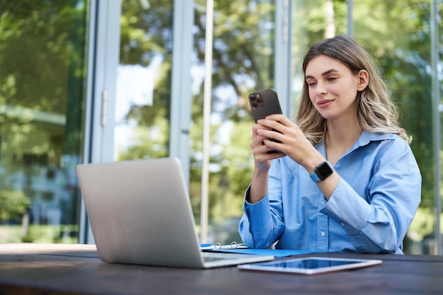 Photo portrait of saleswoman working outside office sititng with laptop using mobile phone digital nomad w