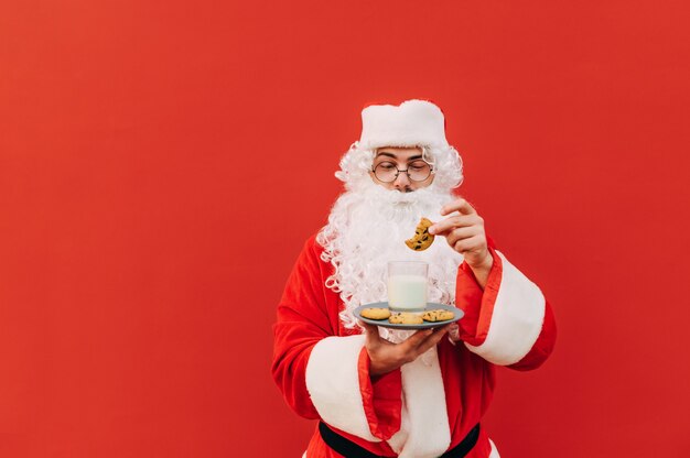 Portrait of a Santa Claus holding a plate with cookies and a glass of milk