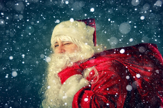 Portrait of Santa Claus. Santa Claus carries a bag with gifts. Christmas Fantasy.