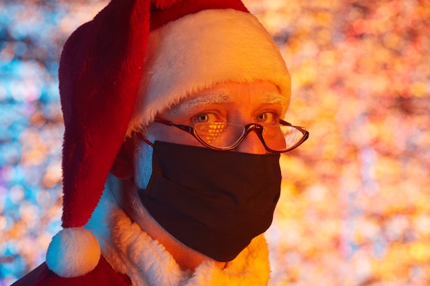 Portrait of Santa Claus in Santa hat wearing protective mask celebrating Christmas holiday