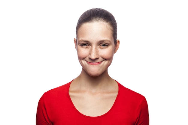 Portrait of satisfied funny woman in red tshirt with freckles looking at camera