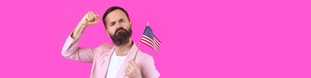 Portrait of a satisfied young man with a beard with an American flag on a red studio background Great US patriot and defender of freedom