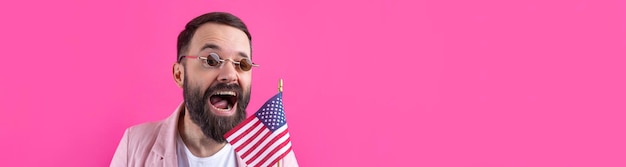 Portrait of a satisfied young man with a beard with an American flag on a red studio background Great US patriot and defender of freedom