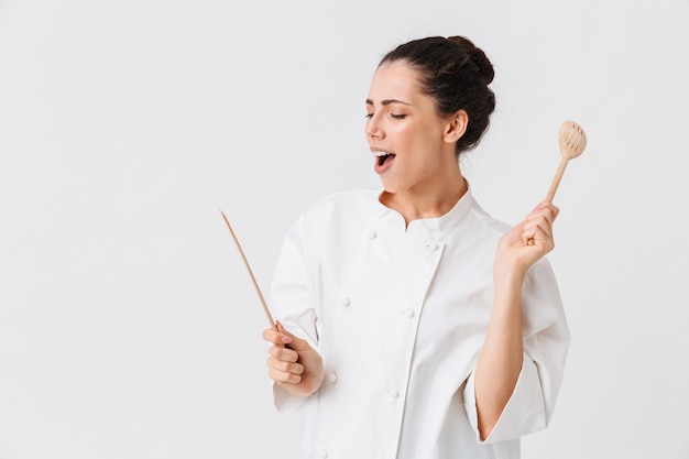 Portrait of a satisfied young woman with kitchen utensils