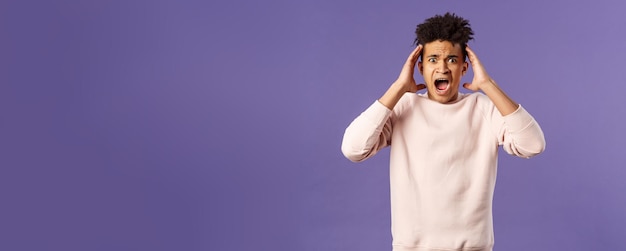 Photo portrait of scared and anxious young hispanic handsome man in panic shaking hands nead head screamin