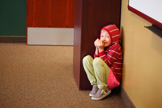 Photo portrait of scared child hiding by wall