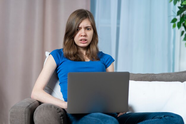 Portrait of scared stressed frighten teen girl young afraid beautiful woman looking at screen of her