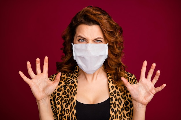 Portrait of scary lady showing claws wear medical mask isolated over dark maroon burgundy color background