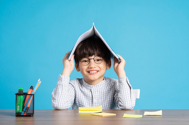 Portrait of school boy sitting and studying on a blue background