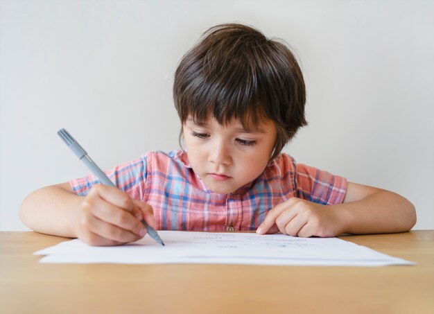 Portrait of school kid boy sitting alone doing homework