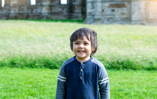 学校の子供の肖像画を探検し、夏の修学旅行で歴史について学ぶ、古い修道院の背景のぼやけた遺跡で一人で立っている幸せな子供男の子