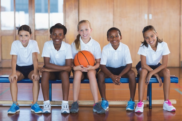 バスケットボールコートに座っている学校の子供たちの肖像画
