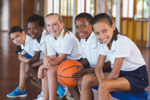 バスケットボールコートに座っている学校の子供たちの肖像画