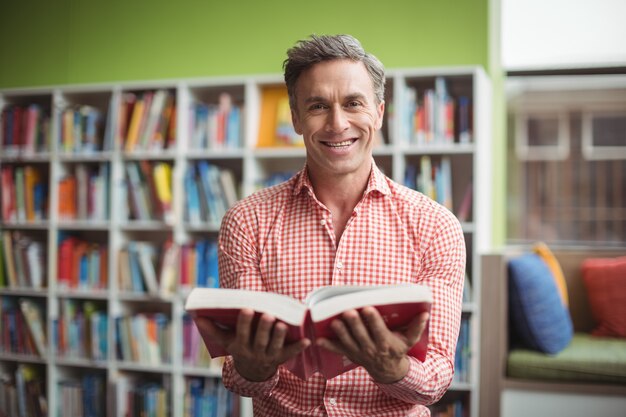 Portrait of school teacher holding book in library