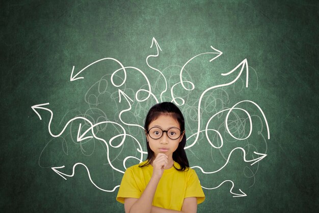 Portrait of schoolgirl against arrow symbols on blackboard