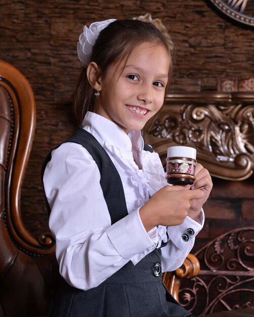 Портрет школьницы, пьющей чай в комнате с винтажным интерьером