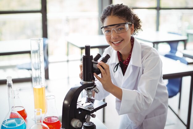 Портрет школьницы, экспериментирующей на микроскопе в лаборатории