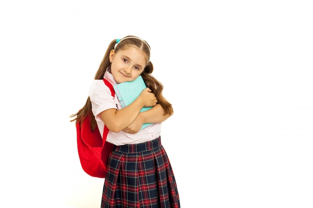 Ritratto di una studentessa in uniforme in piedi su sfondo bianco