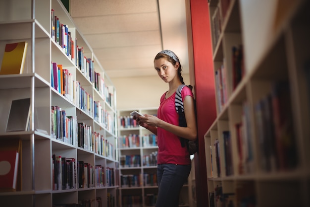 Portrait of schoolgirl using digital tablet in library