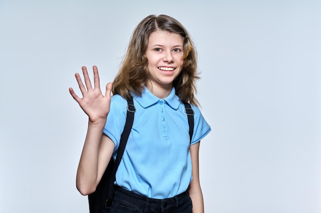 Ritratto di studentessa con zaino che guarda l'obbiettivo salutando o arrivederci