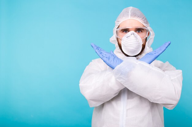 Portrait of scientist virologist wearing protective suit, glasses and respirator showing STOP