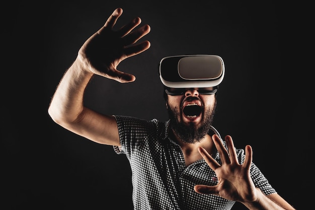 Portrait of a screaming bearded man in a helmet of virtual reality Studio shot Black background