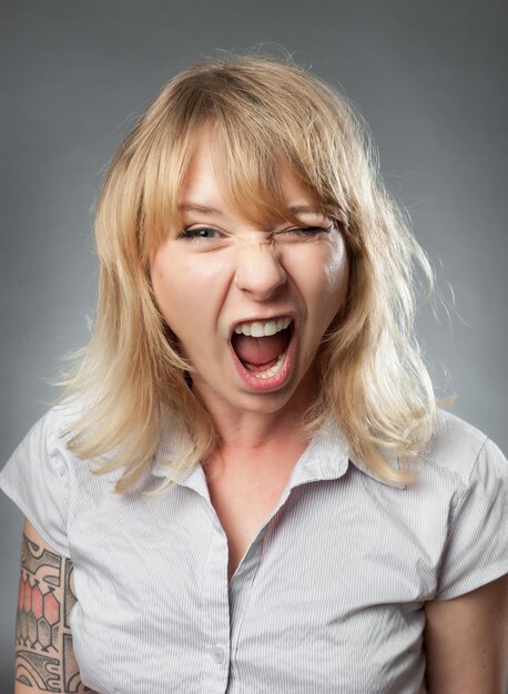 Photo portrait of screaming mid adult woman in formals against gray background