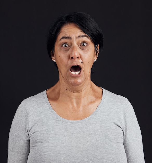 Portrait screaming and senior woman with fear shocked and news with mental health scared and stress Face elderly lady and mature model with emoji afraid and retirement on dark studio background