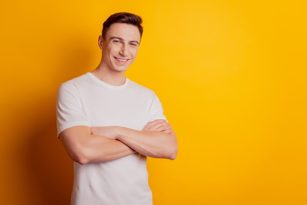 Portrait of self-assured confident guy crossed arms toothy smile look camera on yellow background