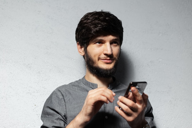 Портрет уверенного в себе молодого парня с помощью смартфона.