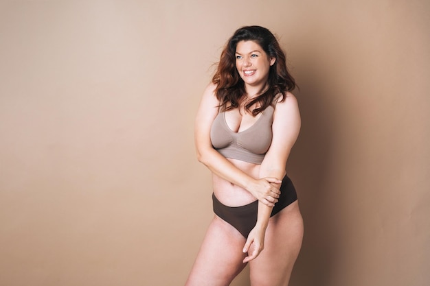 Photo portrait of self loving woman plus size in underwear on beige background body love