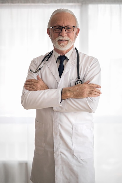 Portrait of senior adult male doctor standing in his office