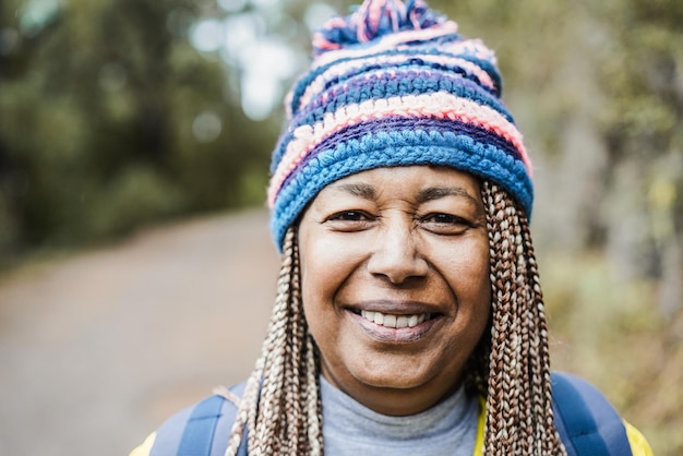 Ritratto di donna africana anziana che si diverte durante la giornata di trekking nella foresta di montagna focus sul viso